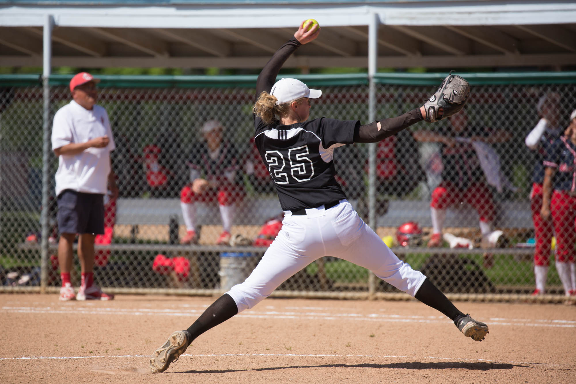 Female student athlete pitching a softball during a game.