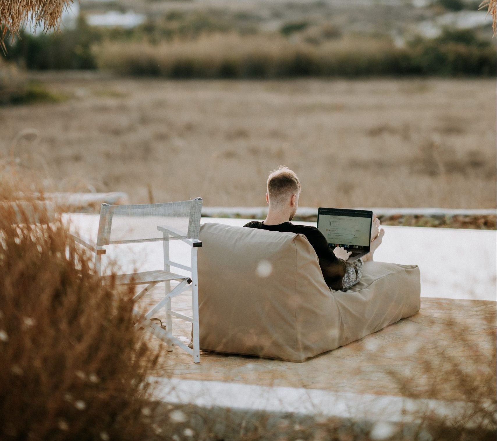 person in a chair outside holding a laptop